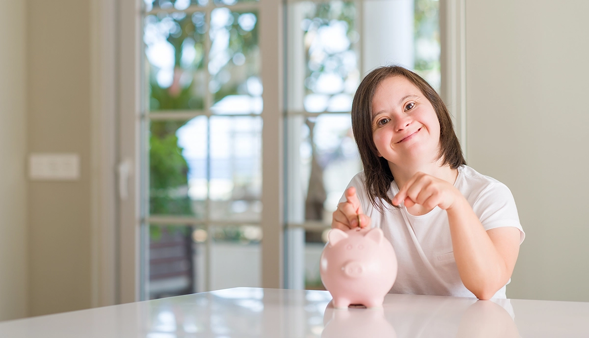 Give sitting at table putting coins into a piggy bank